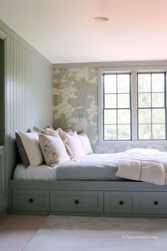 a bed sitting under a window in a bedroom next to a wallpapered wall