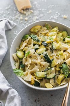 a bowl filled with pasta and vegetables next to two chopsticks on the side