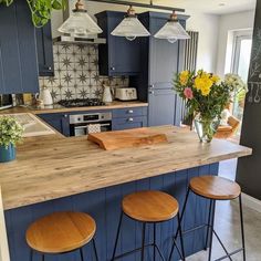 a kitchen with blue cabinets and wooden stools next to an island in the middle