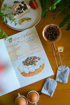 an open menu on a wooden table next to some eggs and other food items in bowls