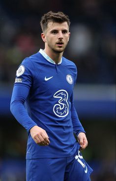 a man in blue soccer uniform standing on the field with his hands behind his back