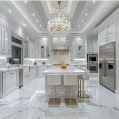 a large kitchen with marble floors and white cabinets, chandelier above the island