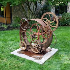 a metal sculpture sitting on top of a cement slab in the middle of a grass covered field