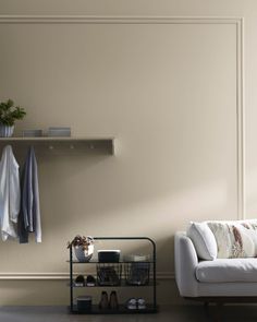 a white couch sitting next to a shelf filled with shoes and sweaters on top of it