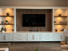 a living room with white cabinets and a flat screen tv mounted on the wall above it