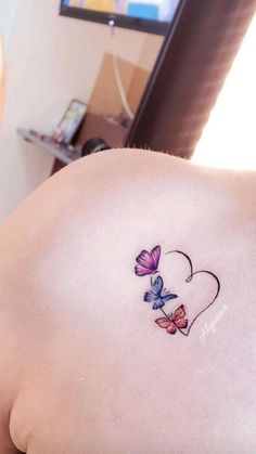 a woman's back with butterflies on her shoulder and the word love written in it