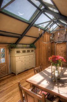 the dining room table is set with flowers in vases on it, and there's a skylight overhead