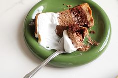 a piece of cake on a green plate with whipped cream