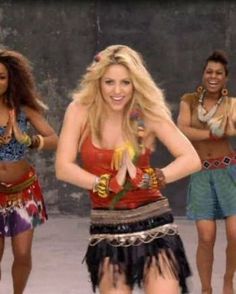 a group of young women dancing together in colorful outfits and headbands, with their hands on their hips