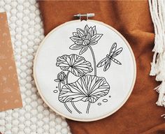 a cross - stitch pattern with flowers and dragonflies on it, next to a piece of fabric