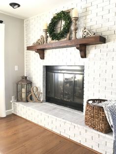 a white brick fireplace with candles and wreaths on the mantel above it in a living room