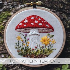 a red and white mushroom with daisies on it's side is featured in this embroidery pattern