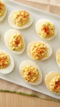 deviled eggs on a white tray with mustard sprinkled on them and seasoning