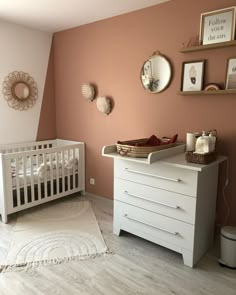 a baby's room with a crib, dresser and mirror on the wall