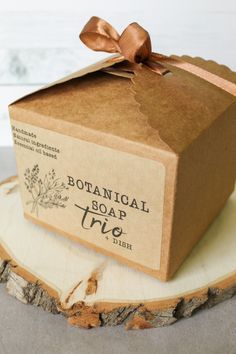 a soap bar wrapped in brown paper on top of a tree stump with a bow