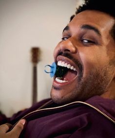 a man is smiling while holding a toothbrush in his mouth