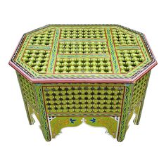 an ornately decorated green and pink table with drawers on one side, in the shape of a hexagonal box