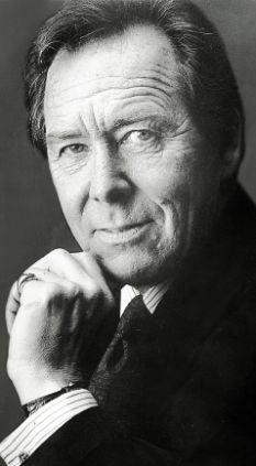 black and white photograph of a man with his chin resting on his hand, looking at the camera