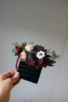 a person holding a flower arrangement in their hand