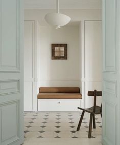 an open door leading to a white room with a bench and chair in the corner