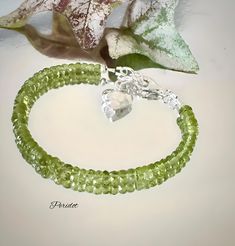 This elegant gemstone bracelet features 5.5mm genuine faceted AAA Peridot rondelle stones, radiating with vibrant sparkle. The stunning green Peridot beads are perfectly complemented by 3.5mm Karen Hill Tribe Silver beads, adding a touch of refined detail. The bracelet is finished with a sterling silver lobster claw clasp and a sterling silver extender chain, adorned with a delicate Karen Hill Tribe Silver puffed heart charm, allowing the bracelet to adjust from 7 inches to 7.5 inches in length Faceted Green Beaded Bracelets For Gift, Faceted Green Beaded Bracelets As Gift, Gift Green Faceted Beaded Bracelets, Green Gemstone Rondelle Beaded Bracelets, Green Rondelle Bracelets With Faceted Beads, Green Rondelle Bracelets For Jewelry Making, Green Faceted Crystal Bracelet For Jewelry Making, Green Crystal Bracelet, Women Healing