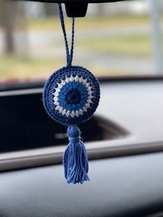 a blue and white crocheted keychain hanging from the dashboard of a car