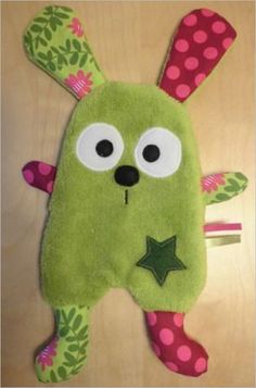 a green stuffed animal laying on top of a wooden table