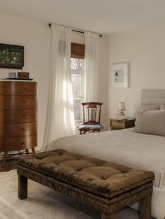 a bedroom with a large bed, dresser and chair in it's center area