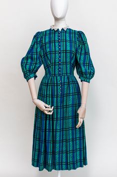 Vintage Austrian blue and green plaid midi dress. This dress features puffed sleeves, cute white lace collar, white buttons. Fitted, fluffy skirt, fastened with buttons at the front. One hidden pocket on the side. Condition: Good vintage condition. No stains or holes. Freshly laundered and ready to wear. Fabric:  52% cotton, 48% modal Measurements: Best Fit: S-M All measurements are taken lying flat and have already been doubled Shoulders (seams): 36 cm / 14'' Sleeves: 50 cm / 19,5'' Chest: 96 c Blue Plaid Dress, Folk Dress, Fluffy Skirt, Dress Cottagecore, Folk Dresses, Hidden Pocket, Lace Collar, Puffed Sleeves, Plaid Dress