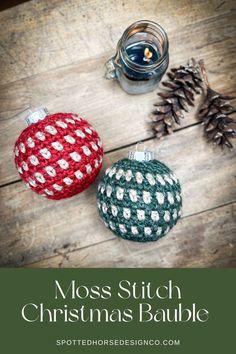 two christmas baubles sitting on top of a wooden table next to a candle