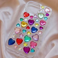 a phone case with hearts on it sitting on a white cloth covered bed sheet in the shape of a heart