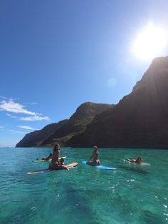 three people on surfboards paddling in the ocean