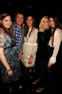 a group of people standing next to each other in front of a dark background with one woman smiling at the camera