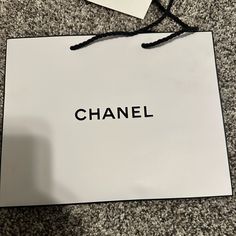 a white bag with the word chanel on it sitting on top of a carpeted floor