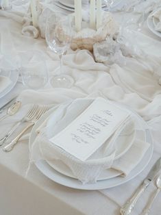 the table is set with white plates and silverware