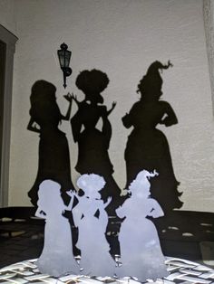 three silhouettes of people standing next to each other on a table with a lamp in the background