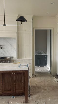 an empty kitchen with marble counter tops and wooden cabinets in the process of remodeling