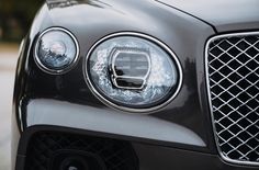 the front end of a black car with chrome grills and headlamps on