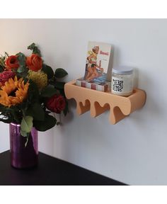 a vase filled with flowers next to a book shelf on a wall above a candle holder