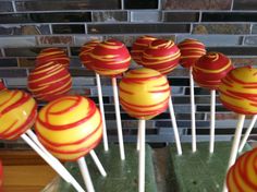 there are many red and yellow lollipops on the stick in front of a brick wall