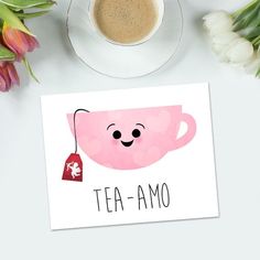 a cup of coffee next to some flowers and a card that says tea - amo