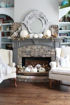 a living room filled with furniture and a fire place covered in white pumpkins on top of a mantle