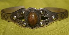 Harvey Era. Old Pawn Navajo Cuff. Hand wrought stampings & repousse work in sterling silver.  Focal Point -  carved Petrified Wood/Quartz - Golden walnut brown. Unmarked. Unsigned. Seasoned Navajo Silversmith. c1950. Very good condition.  SIZE:  6" plus 1" opening WIDTH:  3/4" WEIGHT:  17.1 Grams FREE WORLDWIDE SHIPPING No Returns. No Refunds. Proceeds support the animals I adopt who are rescued by Volunteer Vets from native reserves for 20+yrs. No more Chains, cold, hunger or further misery. All are spayed/neutered to prevent over-population. Could not do this without your help. TY FOR THE LOVE OF ANIMALS 'The greatness of a nation and their moral progress can be judged by the way it's animals are treated.'  -Mahatma Gandhi Vintage Stamped Cuff Bracelet For Anniversary, Vintage Oval Cuff Bracelet With Polished Finish, Antique Stamped Sterling Silver Cuff Bracelet, Vintage Antique Silver Stamped Cuff Bracelet, Vintage Stamped Round Cuff Bracelet, Vintage Collectible Cuff Bracelet With Polished Finish, Vintage Stamped 925 Sterling Silver Cuff Bracelet, Vintage Sterling Silver Concho Cuff Bracelet, Vintage Concho Cuff Bracelet For Gift