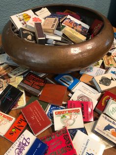 a wooden bowl filled with lots of different types of books on top of a table