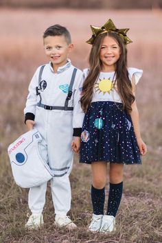 two young children dressed up in space themed outfits, one is holding a backpack and the other is standing next to each other