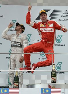 two men standing on top of a podium with their hands in the air and one man holding his fist up