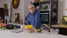 a man standing in front of a cake with lemons on it and other ingredients around him