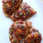 four pieces of chicken covered in sauce on a white plate