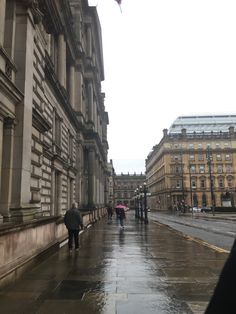 people are walking down the street in the rain