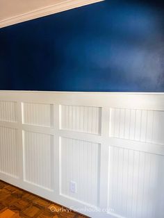 an empty room with blue walls and white paneling